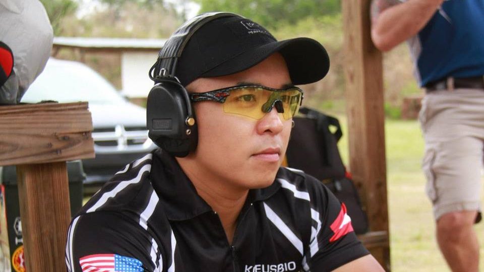 Shooting team member wearing hearing protection and glasses waits during a shooting competition