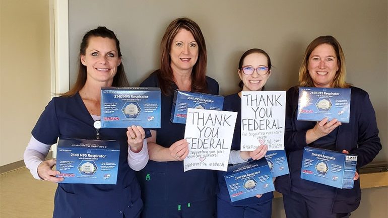 4 nurses holding donated protective gear and homemade signs thanking Federal Ammunition for their donation
